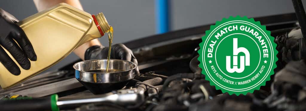Automotive technician performing an oil service with Keys Auto Center's Service Price Match guarantee graphic displayed alongside the engine bay.